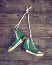 Pair of old green textile sneakers hang from laces