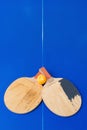 Pair of old pingpong rackets and a dented ball on blue pingpong table