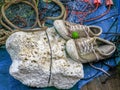 Pair of old sneakers on white foam with fishnet and red rope on the fishing boat. Royalty Free Stock Photo