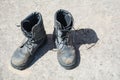 Pair of old used work boots on concrete background. Dirty black leather boots from the army Royalty Free Stock Photo