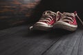 Pair of an old, worn out red canvas sneakers left in the corner Royalty Free Stock Photo