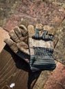 A pair of old and worn work gloves shot outside on a wooden plank, with copy space