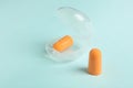Pair of orange ear plugs and case on turquoise background Royalty Free Stock Photo