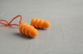 Pair of orange ear plugs with cord on grey background  closeup. Space for text Royalty Free Stock Photo