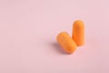 Pair of orange ear plugs on pink background. Space for text Royalty Free Stock Photo