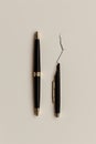 A pair of pens, with one in pieces, illustrating the concept of breakdown or the unexpected interruption