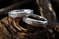 a pair of platinum wedding bands on a charred tree stump