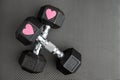 Pair of 15-pound dumbbells on a black gym floor, pink sparkly hearts