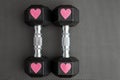 Pair of 15-pound dumbbells on a black gym floor, pink sparkly hearts