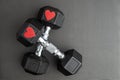 Pair of 15-pound dumbbells on a black gym floor, red sparkly hearts