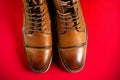 A pair of premium calfskin boots on a red background. Horizontal shot.