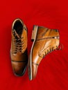 A pair of premium calfskin boots on a red background. Vertical shot.