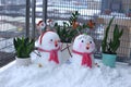 A pair of beautiful little snowmen are piled on the balcony