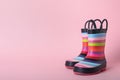 Pair of rainbow rubber boots on pink background. Space for text