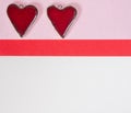 Red ceramic valentines hearts on a pink and white paper background