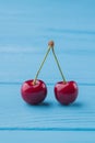 Pair of red cherries on blue wooden desk background. Royalty Free Stock Photo