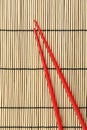 Pair of red chopsticks on bamboo mat, top view Royalty Free Stock Photo