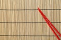 Pair of red chopsticks on bamboo mat, top view. Space for text Royalty Free Stock Photo