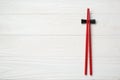 Pair of red chopsticks with rest on white wooden table, top view. Space for text Royalty Free Stock Photo