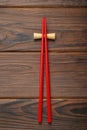 Pair of red chopsticks with rest on wooden table, top view Royalty Free Stock Photo