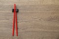 Pair of red chopsticks with rest on wooden table, top view. Space for text Royalty Free Stock Photo