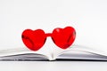 A pair of red heart shaped sunglasses is on top of an open book Royalty Free Stock Photo