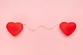 Pair of red hearts connected with a string of twine