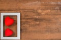 Pair of red hearts in white frame on vintage wooden table, top view. Saint Valentines day background Royalty Free Stock Photo