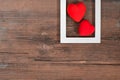 Pair of red hearts in white frame on vintage wooden table, top view. Saint Valentines day background Royalty Free Stock Photo