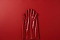 A pair of red latex gloves on a red background. Generative AI image.