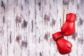 Pair of red leather boxing gloves hanging on a nail on a wooden wall. Royalty Free Stock Photo