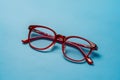 Pair of red plastic rimmed eyeglasses on blue background, stylish Royalty Free Stock Photo
