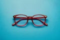 Pair of red plastic rimmed eyeglasses on blue background, stylish Royalty Free Stock Photo