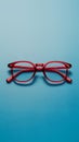 Pair of red plastic rimmed eyeglasses on blue background, stylish Royalty Free Stock Photo