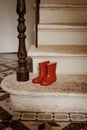 Child`s red wellingtons on stone steps in old french country house