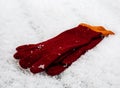 Pair of red wool gloves on a snow covered deck