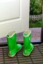 Pair of Reima child rubber boots standing indoors near open door