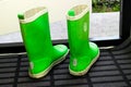 Pair of Reima green rubber boots standing near open door