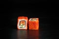 Pair of rolls california with salmon close-up on a dark background