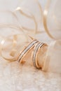 Pair of rose gold and white gold wedding ring with diamonds on beige marble background with ribbon Royalty Free Stock Photo