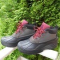 A pair of rugged,waterproof outdoor boots for men, side view, in front of a green hedge
