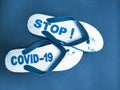 a pair of sandals engraved Stop Covid-19 on a blue background.