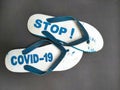 a pair of sandals engraved & x22;Stop Covid-19& x22; on a black background.
