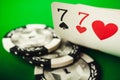 A pair of sevens and poker chips on a green background, poker background. Seven of hearts and seven of spades.