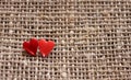 a pair of sharp pins in the form of red hearts stuck in the rough burlap Royalty Free Stock Photo