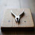 A pair of shiny metallic pliers rests on a textured rectangular wooden block Royalty Free Stock Photo
