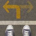 Pair of shoes standing on a road with two way yellow arrow Royalty Free Stock Photo