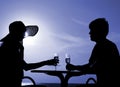 Pair silhouette sit at a table and hold goblets Royalty Free Stock Photo