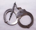 A pair of silver metal handcuffs with a black handcuff key Royalty Free Stock Photo