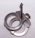 A pair of silver metal handcuffs with a black handcuff key Royalty Free Stock Photo